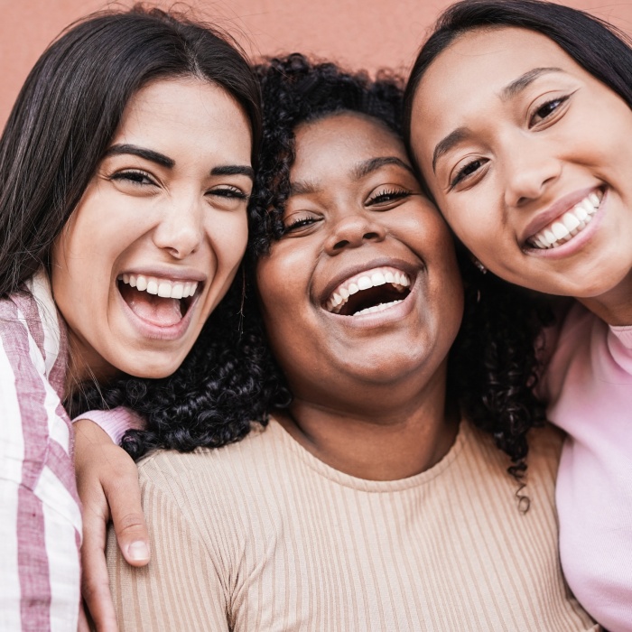 Happy latin women laughing and looking in camera - Millennial girls having fun outdoor taking a selfie